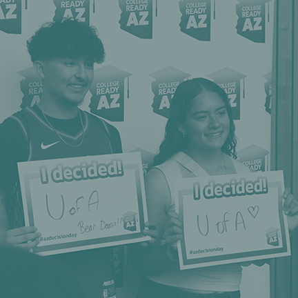 Two students holding signs of which university they picked